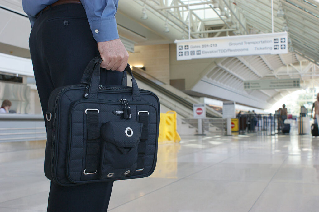 A man walking through the airport with a black nylon briefcase