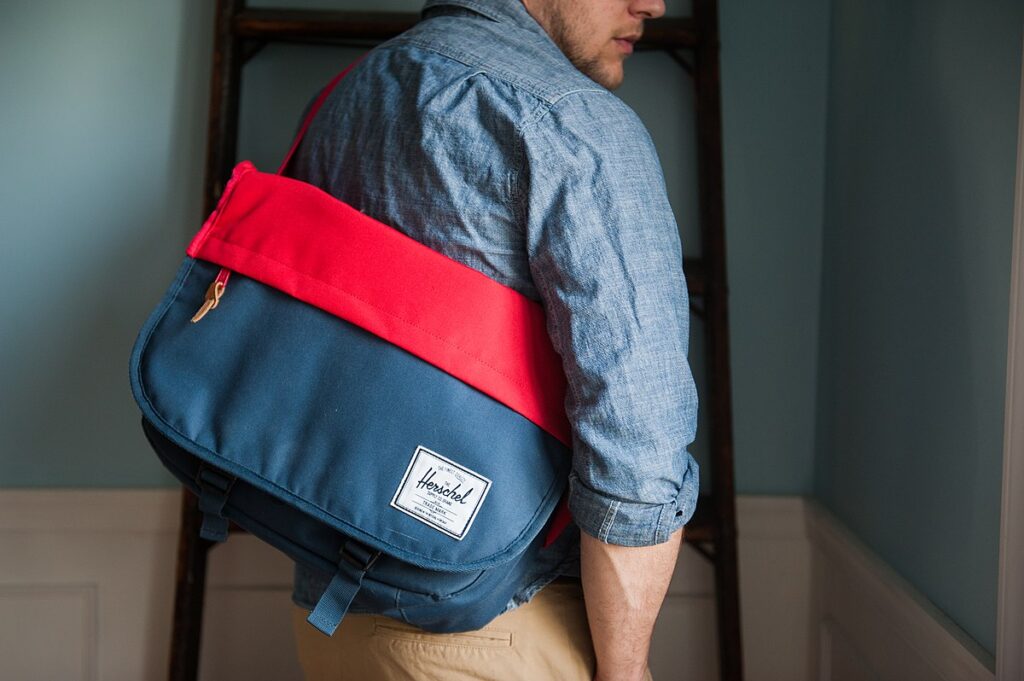 a casually dressed man wearing a Herschel messenger laptop bag