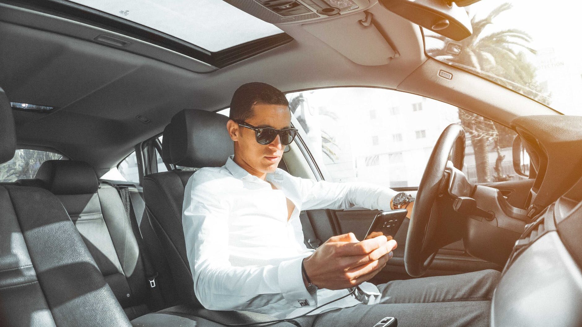 man in white dress shirt holding smartphone